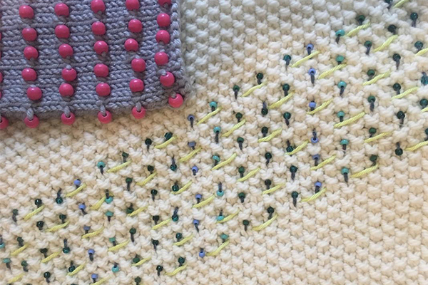 Florence_KnittingwithBeads2 4 balls of yarn in different shades, a hand wearing a knitted handwarmer, knitting needles and a knitted rectangle