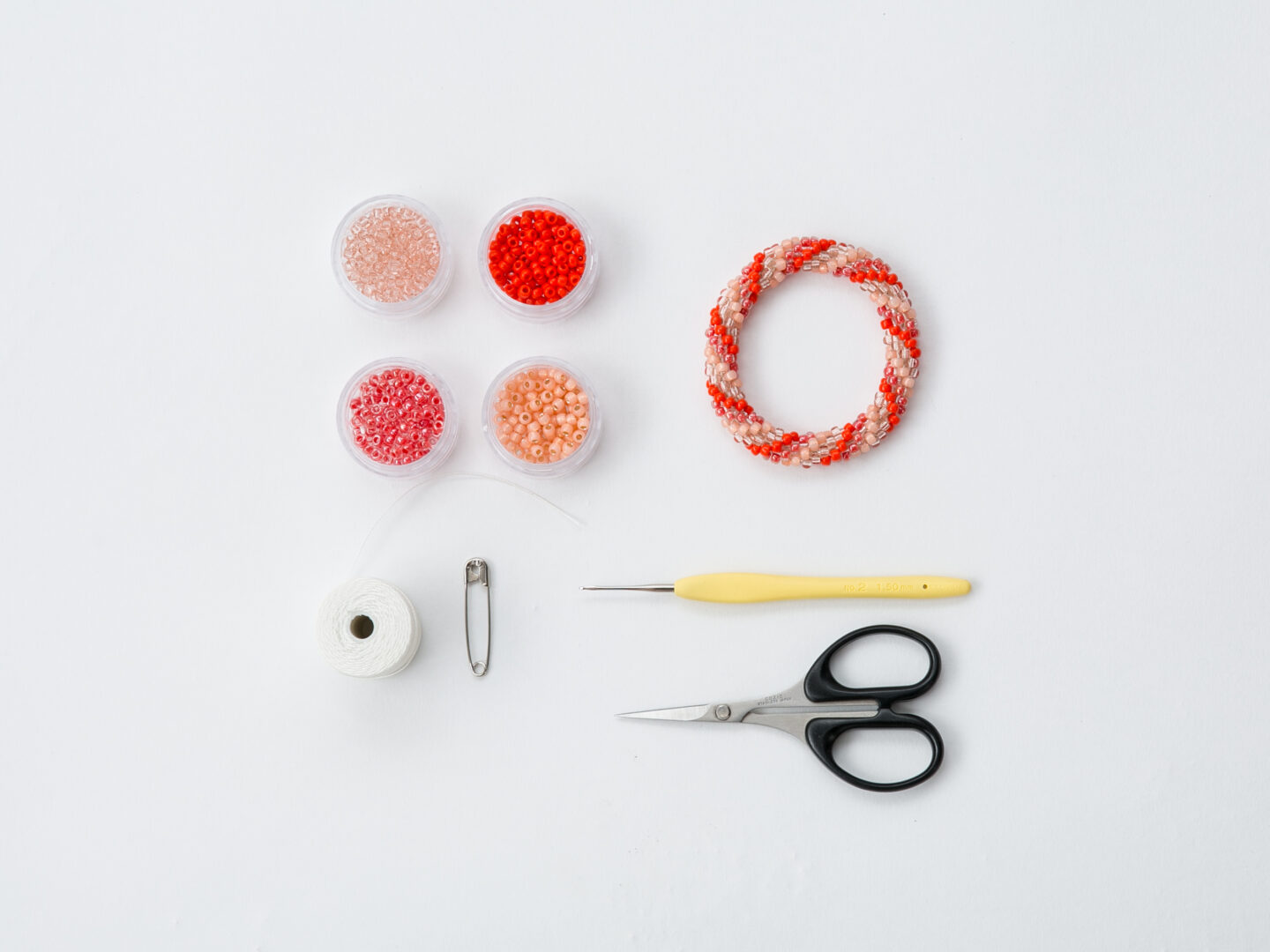 Florence spurling studio 4 balls of yarn in different shades, a hand wearing a knitted handwarmer, knitting needles and a knitted rectangle